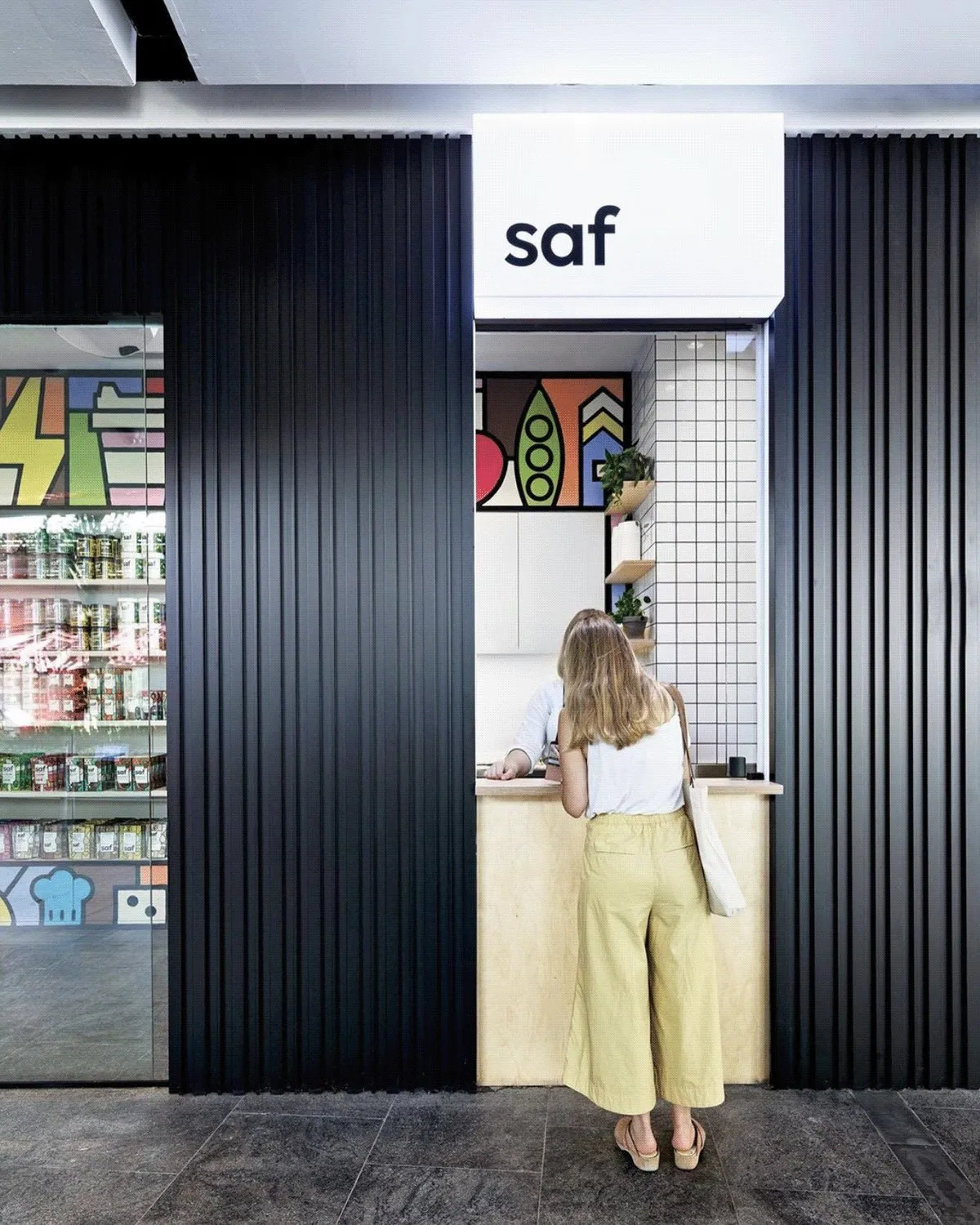 A customer at the plywood counter under the Saf sign, mural to the left.