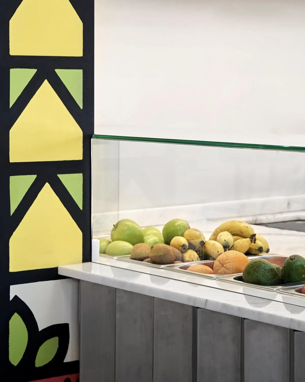 Fresh fruit on the counter in front of a painted yellow and green mural detail.
