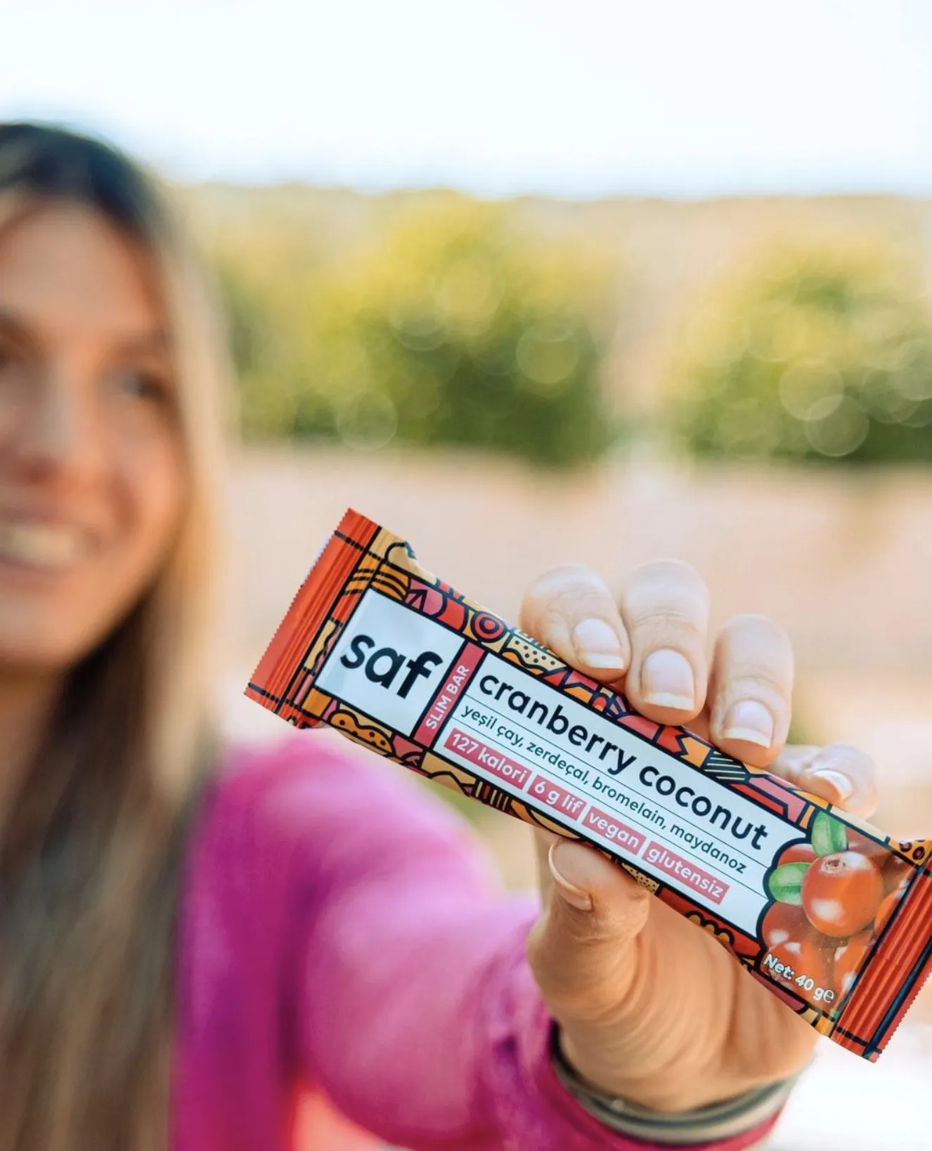 A woman holds up a cranberry coconut bar outdoors.
