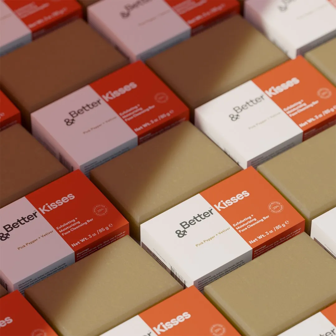 Rows of '&Better Kisses' boxes in pink and orange with olive soap bars.
