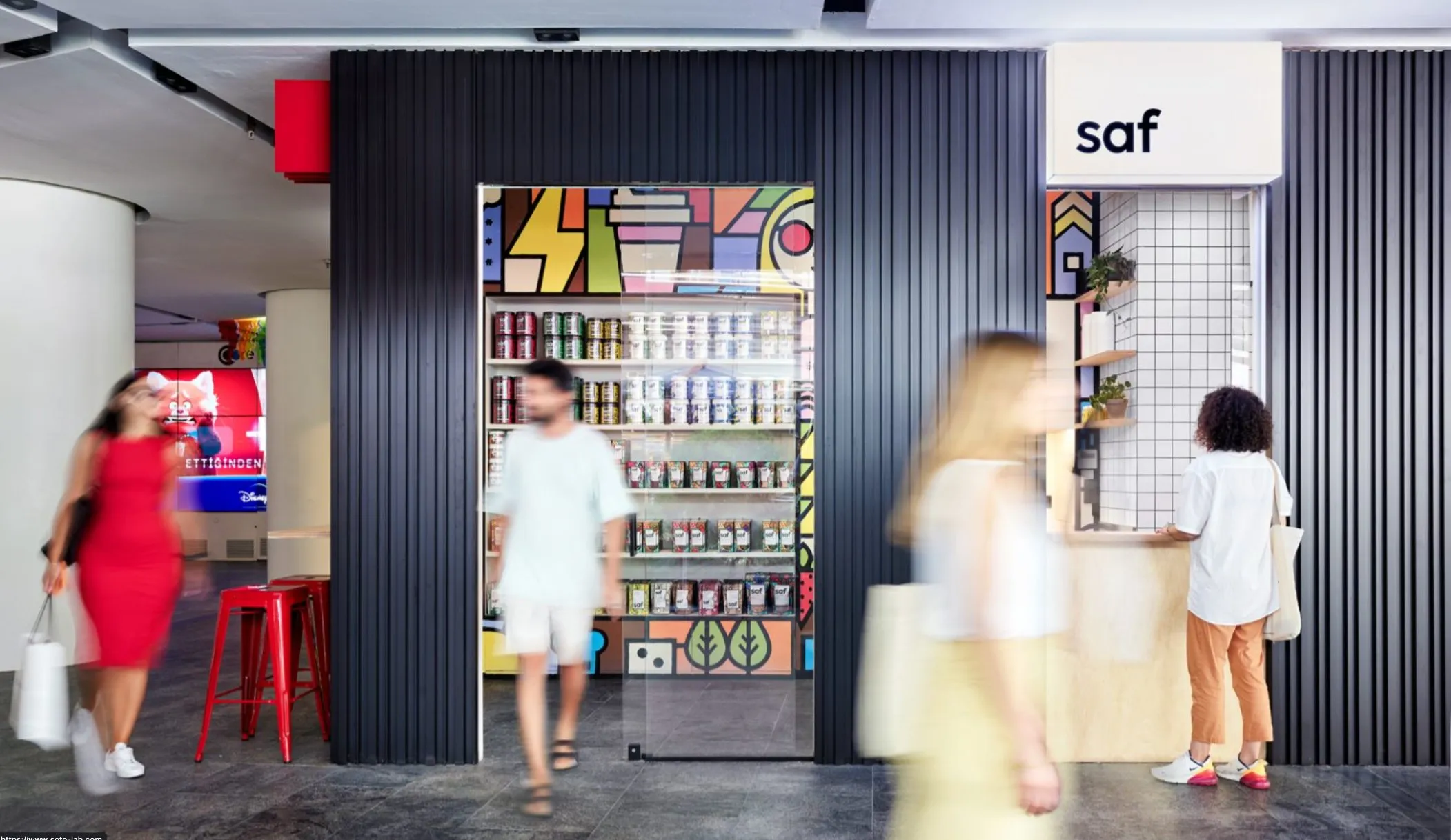 The Saf storefront with a black slatted façade, a painted mural panel and customers at the counter.